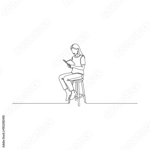 Woman sitting on stool reading book in quiet moment
