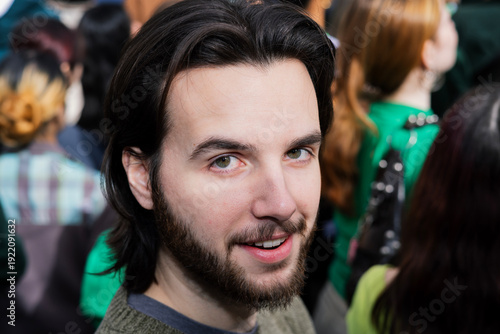 Man looks at camera with ambivalent expression during St Patrick's Day