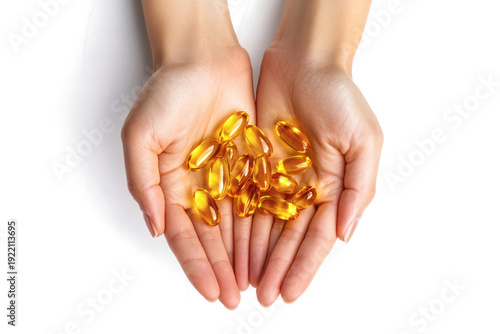 A pair of cupped caring human hands gently holding a generous helping of glistening golden omega three fish oil supplement softgel capsules 