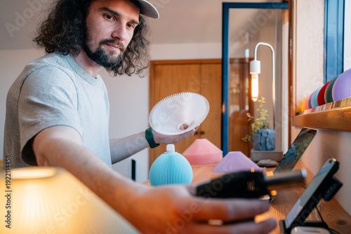 Man handles lamp shade and tool at workbench