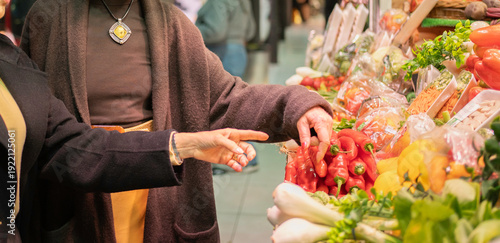 Cuadro en lienzo Shoppers' hands choosing red peppers from a vibrant display of produce at an ind
