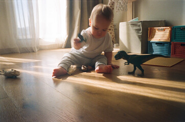 Toddler Playing with Dinosaur Toys At Home.  Film Photo