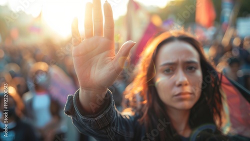 Woman in a crowd, with raised hand and determined expression, during a golden hour protest or rally