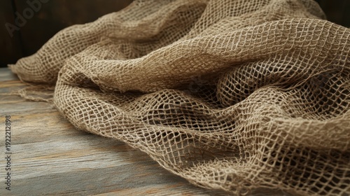 Close-up view of weathered burlap fishing net texture draped over a rustic wooden table surface