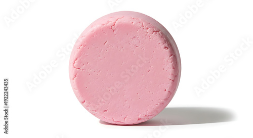 A single round pink object, possibly a bath bomb or soap, casting a shadow on a white background.