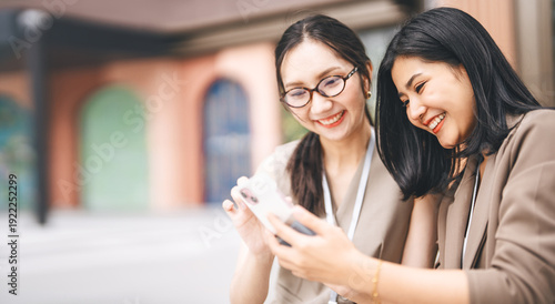 Tableau sur toile Two young adult business women laughing gossip news from social network together