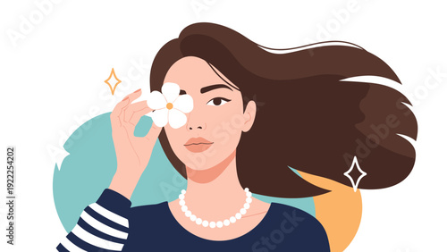 Portrait of a beautiful young woman with long flowing brown hair holding a white flower over her eye for an artistic look.