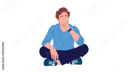 Young man in a blue sweater sitting cross-legged on the floor in a pensive pose with his hand on his chin contemplating ideas.