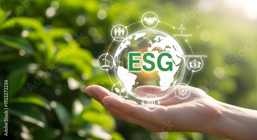 Hand holding a holographic globe representing ESG concepts in a green environment