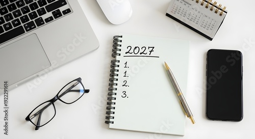 A clean workspace setup featuring a laptop, notebook, and smartphone for organizing goals in 2027