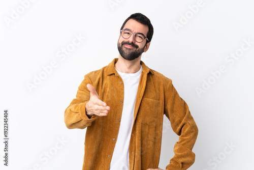 Caucasian handsome man with beard wearing a corduroy jacket over isolated white background shaking hands for closing a good deal