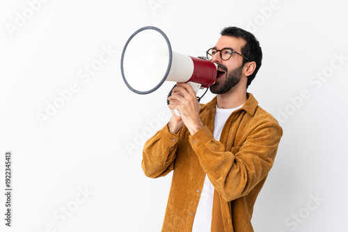 Caucasian handsome man with beard wearing a corduroy jacket over isolated white background shouting through a megaphone