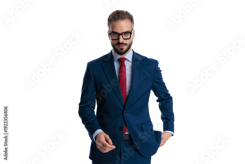 Confident businessman walking and taking hand out of pocket