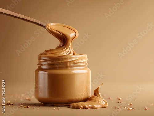 A jar of smooth peanut butter with a spoonful drizzling over the edge, with copy space