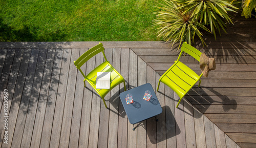 Terrasse dans un petit jardin paysagé et ses plantes vertes au milieu du gazon.