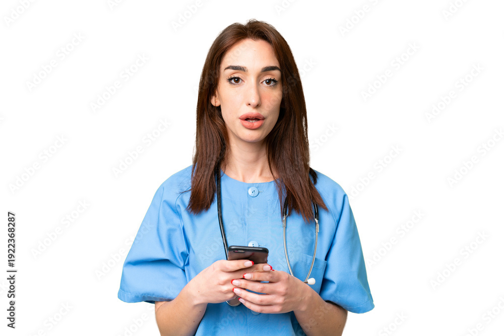 Fototapeta premium Young nurse woman over isolated chroma key background surprised and sending a message