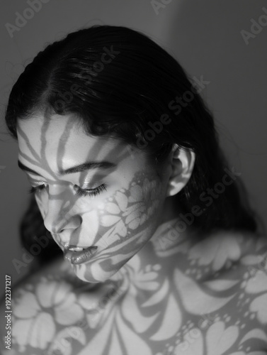 Black and White Artistic Portrait of a Young Woman with Floral Pattern Shadows on Her Face and Shoulders