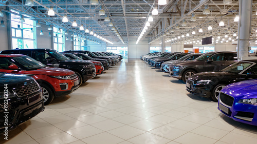 Car dealership showroom interior with rows of new vehicles.