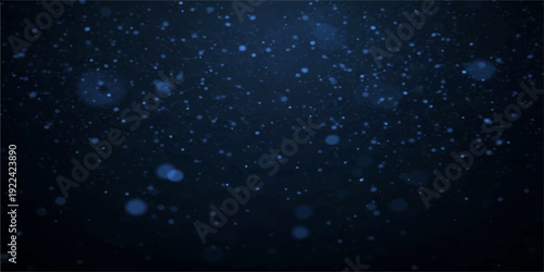 A festive winter night sky filled with falling snowflakes and rain drops on a dark window creates a starry blue galaxy pattern of light and water particles for a Christmas holiday design