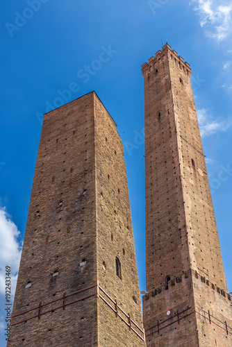 Wallpaper Mural The iconic Asinelli Tower and neighboring Garisenda Tower in Bologna, Italy, known for their impressive medieval architecture and rich history under a clear blue sky. Torontodigital.ca