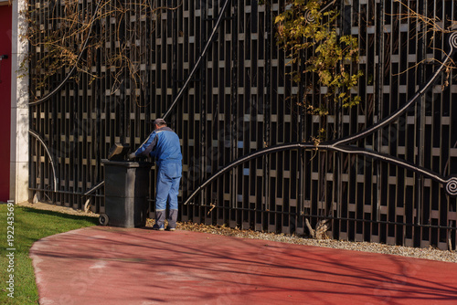 Middle aged man handling trash bin in park municipal cleaning service concept