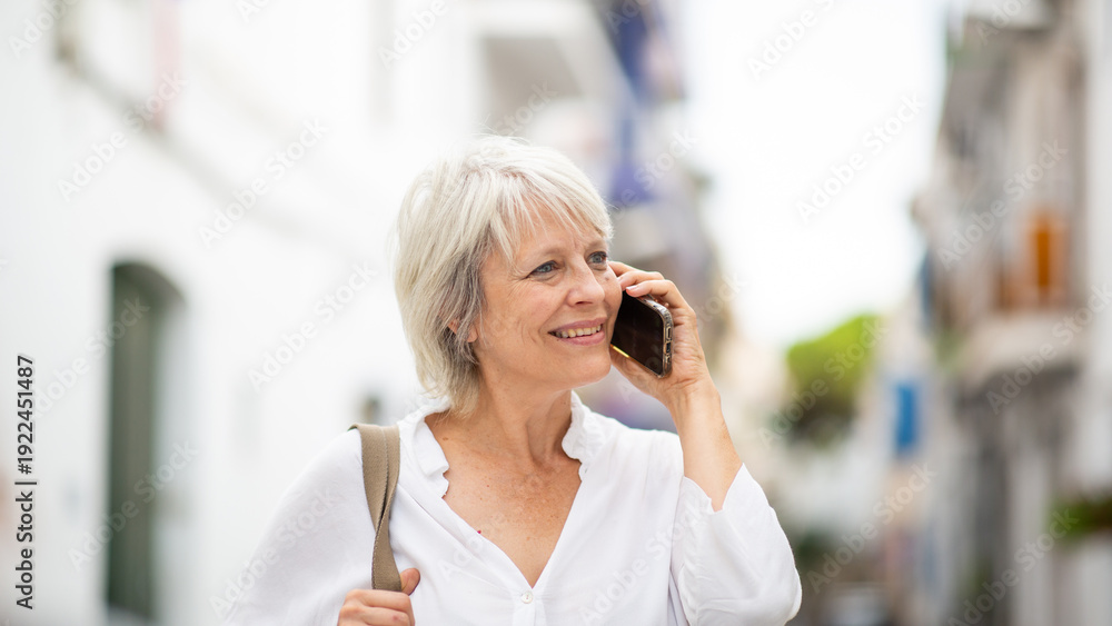 Fototapeta premium Happy senior woman talking on smartphone outdoors