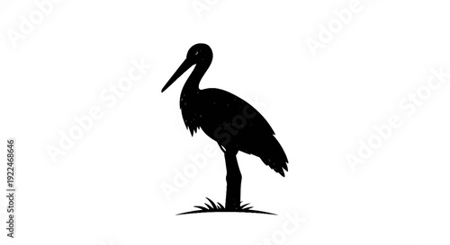 Silhouette of a stork standing on a post amidst grass