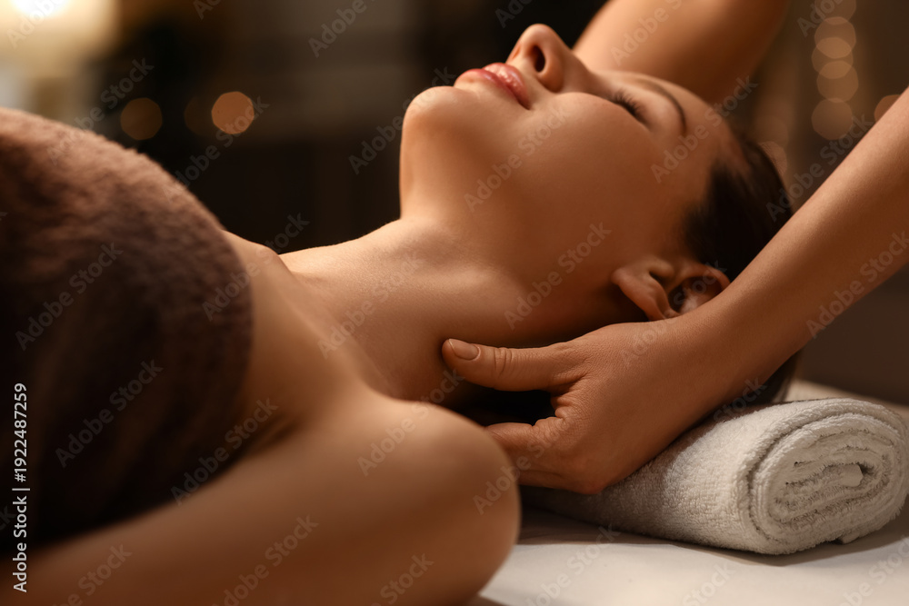 Naklejka premium Beautiful woman having facial massage in dark spa salon, closeup