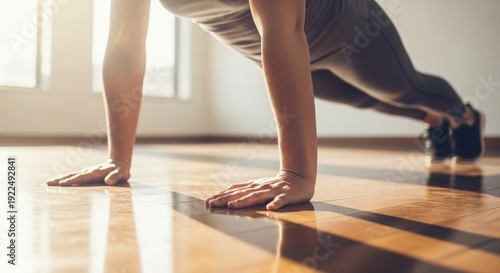A person is doing push ups on a wooden floor in a well lit room