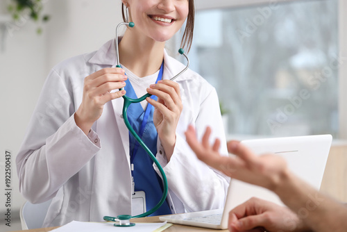 Female doctor with stethoscope and patient at table in clinic
