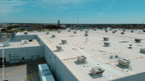 White membrane roof shows aligned industrial RTU HVAC units, mechanical near Premier Dr and Clearview Park, east of US‑75 highway frontage, Spring Creek Pkwy surrounding district, Plano, Texas