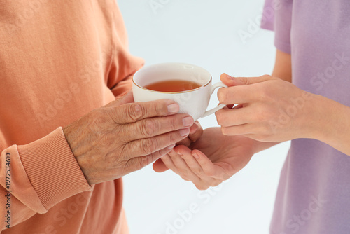 Young woman giving cup of t...