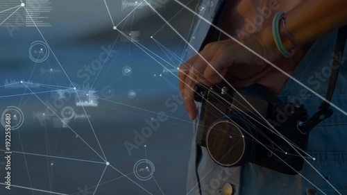 Hand holding camera with network connections and data processing animation overlay