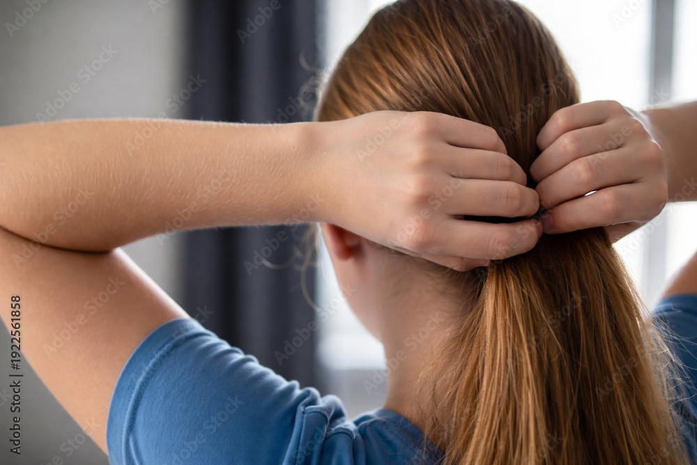 Fototapeta premium Woman hair ponytail hand rear view tying hairstyle indoor, casual morning routine with calm focus at home