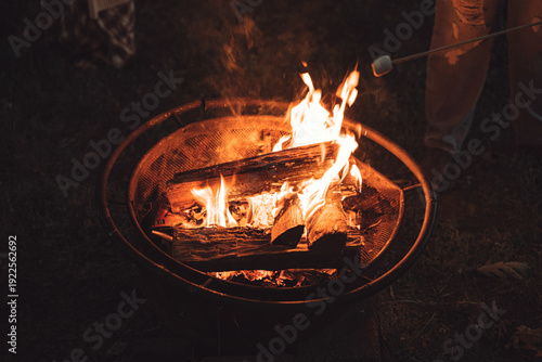Foto Burning wood logs in backyard fire pit at night with marshmallow