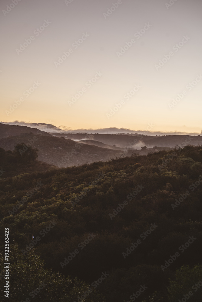 Obraz premium Misty hills and rolling mountains at sunrise with copy space