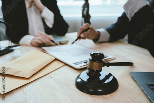 Fotografia Two lawyers discuss legal documents at a desk, with a scale of justice and gavel symbolizing law, authority, and professional legal consultation in a modern office