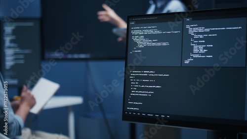 Asian Male developer leading a team meeting, pointing to code on a big monitor while reviewing an AI chatbot module. Concept of collaboration, debugging for coding teamwork in a tech company office.