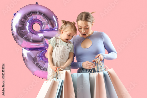 Little girl with her mother, shopping bags and balloon in shape of figure 8 on pink background. International Women's Day