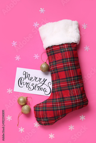 Christmas sock with greeting card and balls on pink background