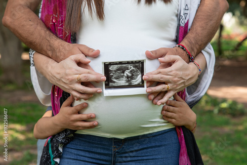 Pregnant woman and her son with ultrasound scan in the park