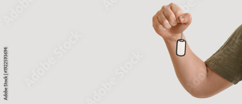 Young Jewish man with military dog tag on light background, closeup