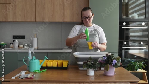 Woman prepares soil for seedlings in the kitchen, home gardening