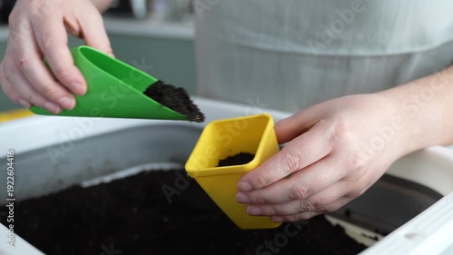 Filling a pot with soil for seedlings, close-up of hands