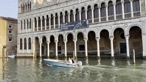Speedboat navigates historic canal with elegant architecture in background