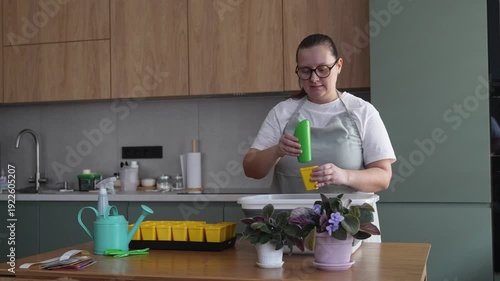 Woman prepares soil for seedlings in the kitchen, home gardening