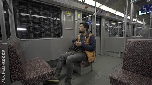 Man takes subway in Berlin, Germany and using smartphone. Male with smart phone on commuter train. Passenger on Berlin subway surfing internet on phone. Fahrgast in der U-Bahn in Berlin, Deutschland. 