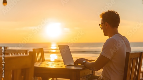 Sunset Serenity: A man immersed in his work, using laptop. with the golden sunset over the ocean, embracing the harmony of business and a stunning natural backdrop.