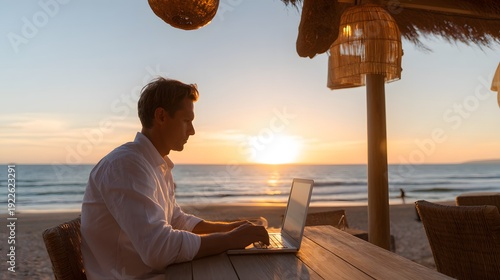 Work-Life Balance Beachside: A focused individual finds a perfect blend of work and leisure, immersed in his task while enjoying the beauty of the coastal sunset and tranquil beach scenery.