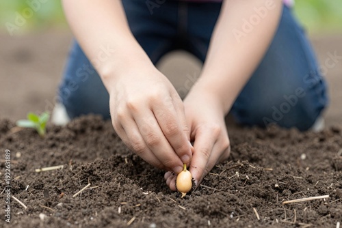 A person kneeling in a garden, planting a seed